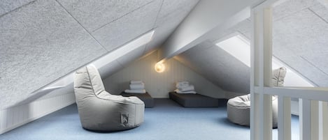 Una habitación moderna en ático con techo inclinado, un banco empotrado y una lámpara fijada a la pared.