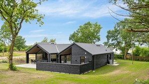 A modern black building with a sloped roof, large windows, and a covered outdoor seating area. - VillaVilla 904 - Odsherred, Nordsjælland (Højby)