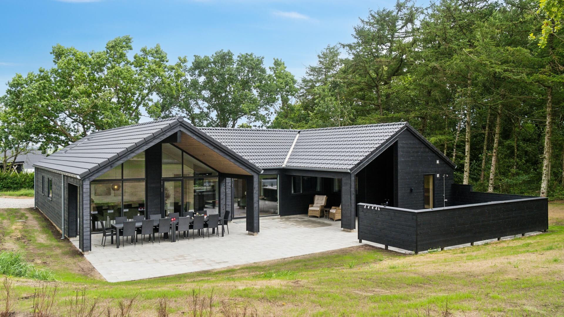 A modern house with a large patio area, a dining setup, and a separate lounge area.
