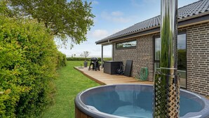 A backyard with a hot tub, a barbecue area, and a wooden deck. - VillaVilla 950 - Spodsbjerg, Fyn og øer (Rudkøbing)