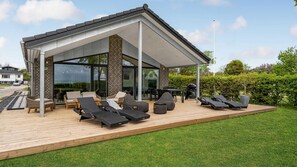 Eine moderne Außenpatio mit Liegestühlen, einer Grillgegend und einem überdachten Sitzbereich.