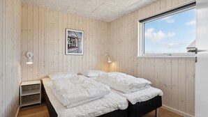 A bedroom with a bed, two wall-mounted lamps, a framed picture, and a window with a view. - VillaVilla 961 - Marielyst, Lolland/Falster/møn (Idestrup)