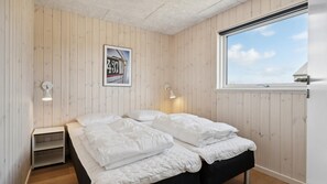 Ein Schlafzimmer mit einem Bett, zwei Wandleuchten, einem gerahmten Bild und einem Fenster mit Blick.