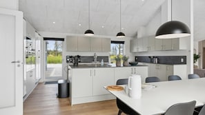 Una cocina moderna con armarios blancos, una isla grande e iluminación colgante.