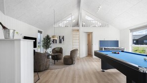 Um espaço moderno em ambiente interno com mesa de bilhar, área de estar e vista para o exterior.