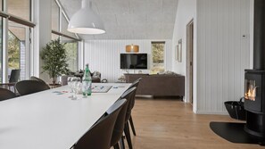 A modern kitchen with a dining area, a large window, and a built-in fireplace. - VillaVilla 915 - Skåstrup Strand, Fyn og øer (Bogense)