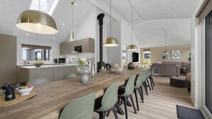 A modern kitchen with a central island, pendant lighting, and a dining area with chairs and a table. - VillaVilla 915 - Skåstrup Strand, Fyn og øer (Bogense)