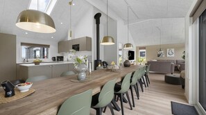 Uma cozinha moderna com uma ilha central, iluminação pendente e uma área de jantar com cadeiras e mesa.