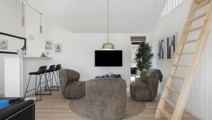 A modern living room with a flat-screen TV mounted on the wall, two bean bag chairs, a small coffee table, and a wooden ladder leaning against the wall. - VillaVilla 915 - Skåstrup Strand, Fyn og øer (Bogense)