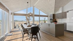 Eine moderne Küche mit großen Fenstern, einem Essbereich mit Tisch und Stühlen und Blick auf die Wüstenlandschaft.