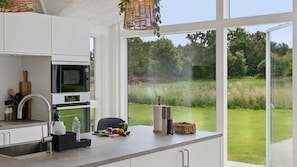 Eine moderne Küche mit einem großen Fenster, einer Mikrowelle und einem Spülbecken.
