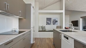 Une cuisine moderne équipée d’un four encastré, d’un évier et d’un coin repas avec un banc.