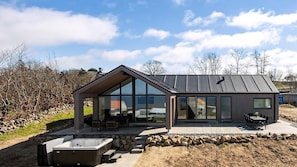 A modern house with large windows, a patio with outdoor furniture, and a hot tub. - VillaVilla 927 - Hasle, Bornholm (Hasle)
