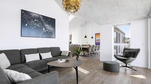 A modern living room with a grey sofa, a round coffee table, and a dining area with chairs. - VillaVilla 927 - Hasle, Bornholm (Hasle)