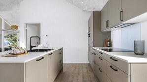 Uma cozinha moderna com uma ilha central, forno embutido e janela com vista para o verde.
