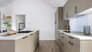 A modern kitchen with a central island, a built-in oven, and a window overlooking greenery. - VillaVilla 927 - Hasle, Bornholm (Hasle)