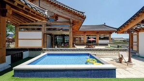 A traditional Korean-style building with a swimming pool and outdoor seating area.