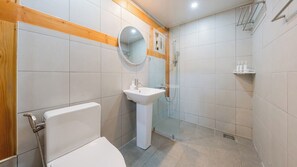 A bathroom with a toilet, sink, mirror, shower, and a towel rack.