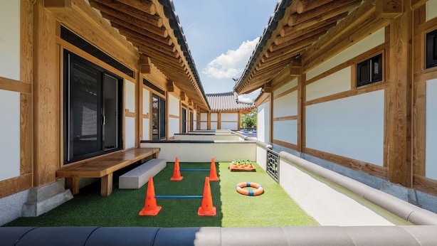 A traditional wooden building with a covered walkway and a small play area with cones and a ball.