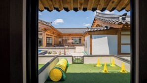 A traditional Korean-style building with a wooden structure, a courtyard with a pool, and a view through a window.