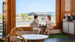 A couple dining at a wooden table with a view of traditional buildings and a mountain in the background.