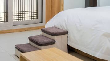 Un lit recouvert d’une couverture blanche, une table en bois et un petit escalier menant au lit.