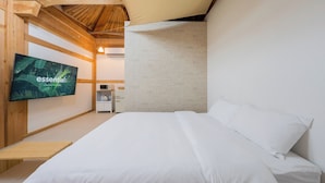 A bedroom with a bed, a television, a microwave, and a small cabinet.