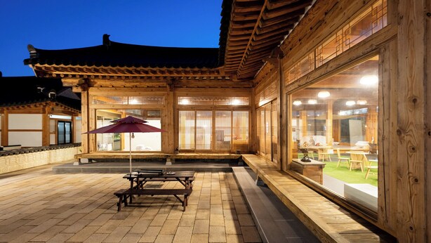 A traditional wooden building with a tiled patio, a table with benches, and a large window.