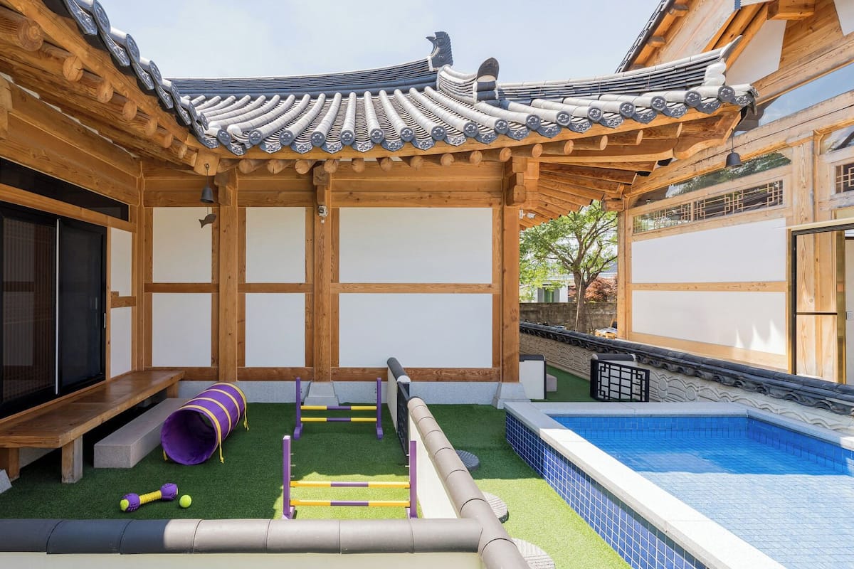Perinteinen japanilaistyylinen rakennus, jossa on puinen ulkoverhous, tatamimattoja lattialla, pieni sisäuima-allas sekä leikkialue, jossa on liukumäki ja esteitä.