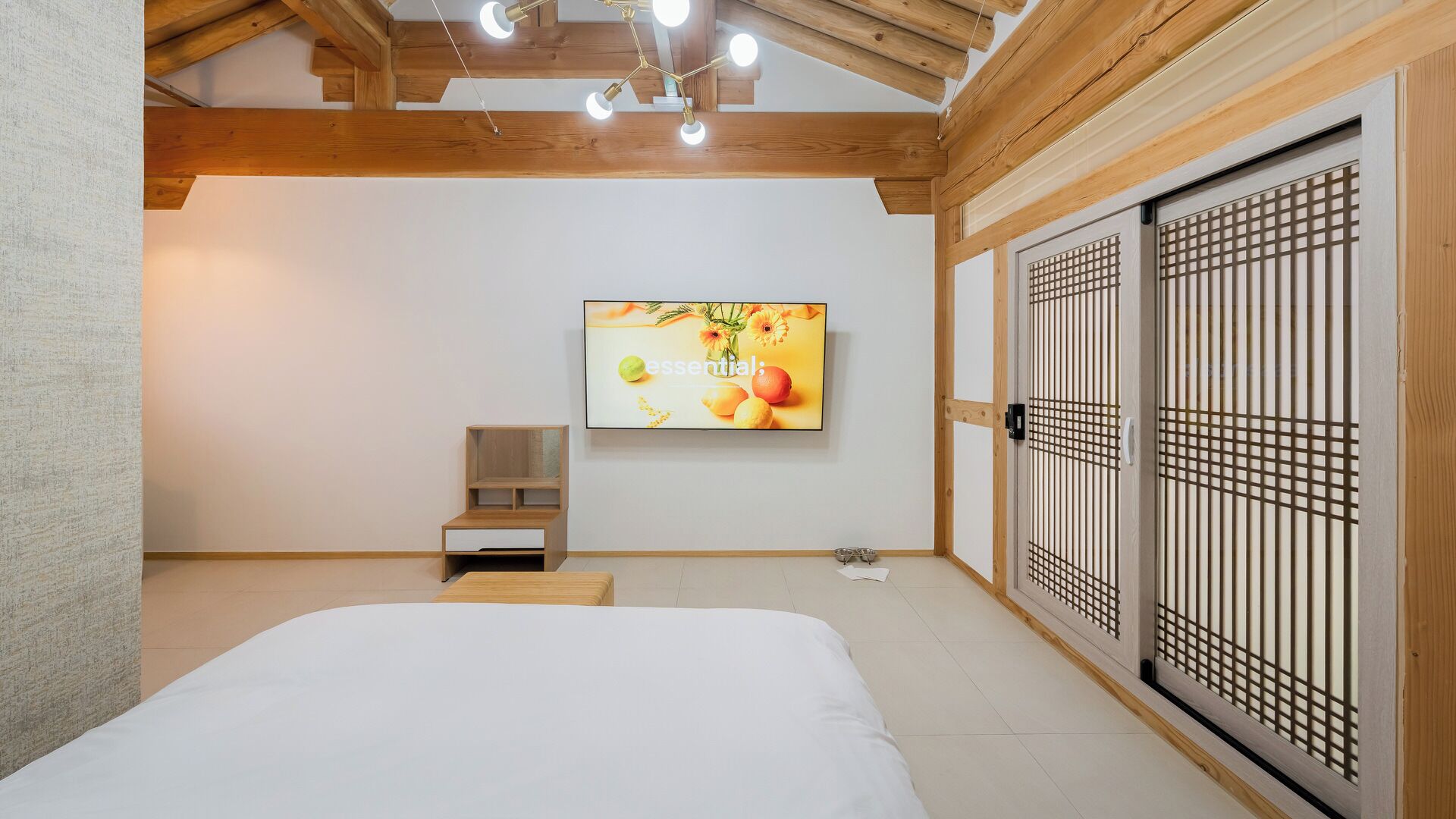 Un dormitorio con cama, televisor, armario de madera y un pequeño mueble de madera.