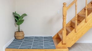 Eine Holztreppe mit Handlauf, einem Blumentopf und einem gemusterten Teppich.