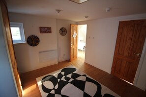 A hallway with wooden flooring, a black and white rug, a wooden door, and a window. - Rustic cottage with sea views (Southwick)