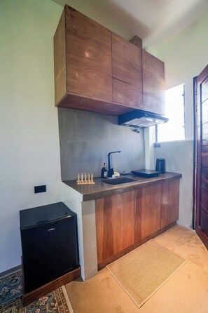 A compact kitchen with wooden cabinets, a built-in stove, and a small refrigerator.