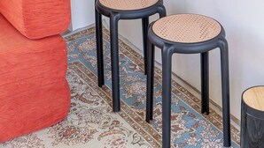 Une petite pièce moderne avec un banc en bois, deux tabourets et une radio posée sur une étagère.