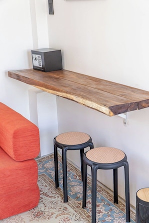A small, modern room with a wooden bench, two stools, and a radio on a shelf.