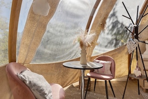 A tent interior with a round table, two chairs, and a decorative item on the right. - Guest Room “Bulle des Châteaux” with Wi-Fi and Pool (Chitenay)