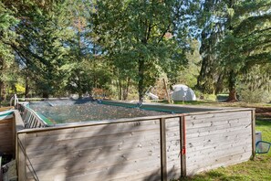 A swimming pool with a wooden deck and a covered area, surrounded by trees. - Guest Room “Bulle des Châteaux” with Wi-Fi and Pool (Chitenay)