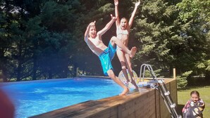 Una piscina con cubierta de madera y escalera de metal.