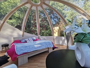 A cozy room with a bed, a small stool, and a large window overlooking a forest. - Bed and Breakfast 'Bulle Des Châteaux' with Shared Terrace, Shared Garden and Wi-Fi (Chitenay)