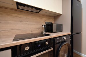 Een kleine keuken met een magnetron, fornuis, vaatwasser en wasmachine.