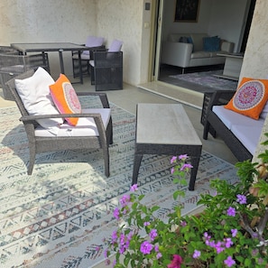 Un espace patio aménagé avec des meubles en osier, un tapis à motifs et une vue sur le salon.