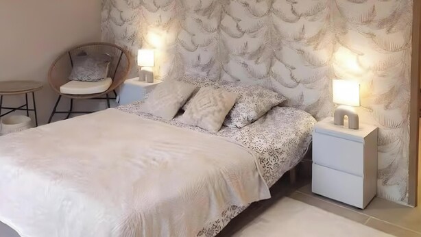 A bedroom with a bed, nightstands, a chair, and a wall with a leaf pattern. - Bed and Breakfast 'Chambre D'hôte Vue Sur Étang' with Shared Pool, Shared Terrace and Wi-Fi (Chitenay)