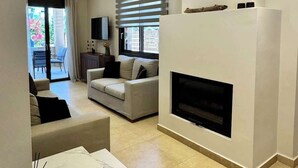 Un saló modern amb una llar de foc, un sofà, una televisió i una zona de menjador.