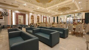 Un amplio vestíbulo de hotel con zonas de estar, una sección de comedor y un techo decorativo.