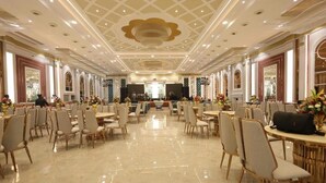 Un amplio salón de banquetes con techos altos, candelabros y filas de mesas y sillas.