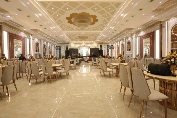 Un amplio salón de banquetes con techos altos, candelabros y filas de mesas y sillas.