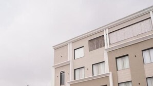 Un hotel con fachada moderna, un acceso cubierto y un patio ajardinado.