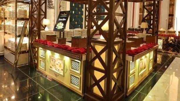 Una estructura tradicional de madera con diseño de celosía, posiblemente una casa de té o una exposición cultural, en un espacio interior bien iluminado con piso pulido.