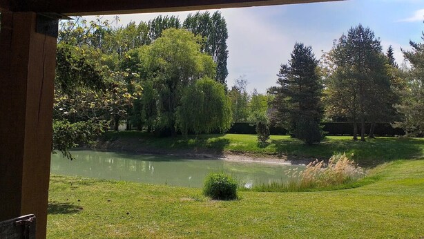 A serene outdoor area with a pond, trees, and a wooden structure. - Bed and Breakfast 'Chambre Quadruple' with Shared Pool, Shared Terrace and Wi-Fi (Chitenay)