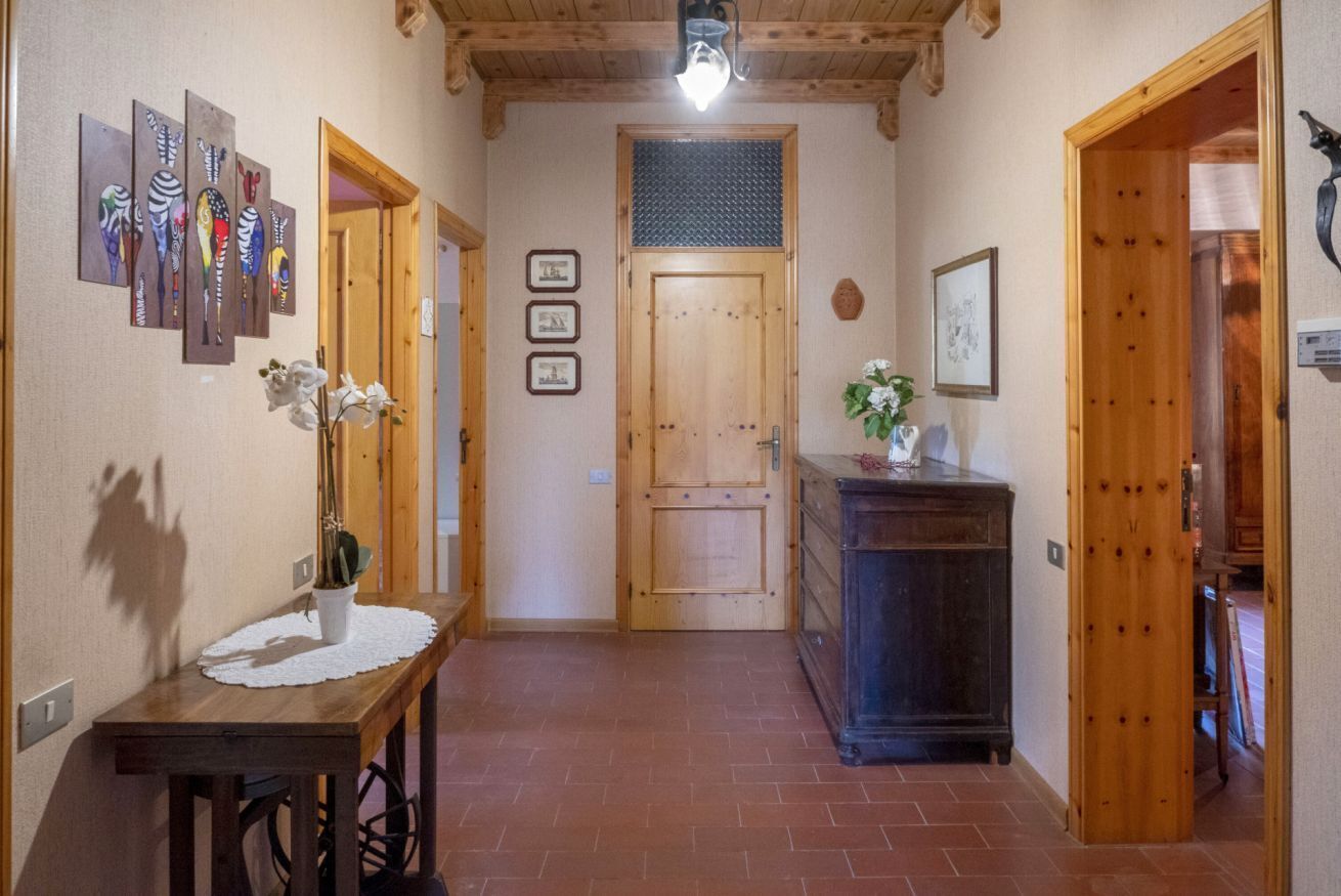 A hallway with wooden doors, a wooden table with a vase, and wall-mounted artwork.